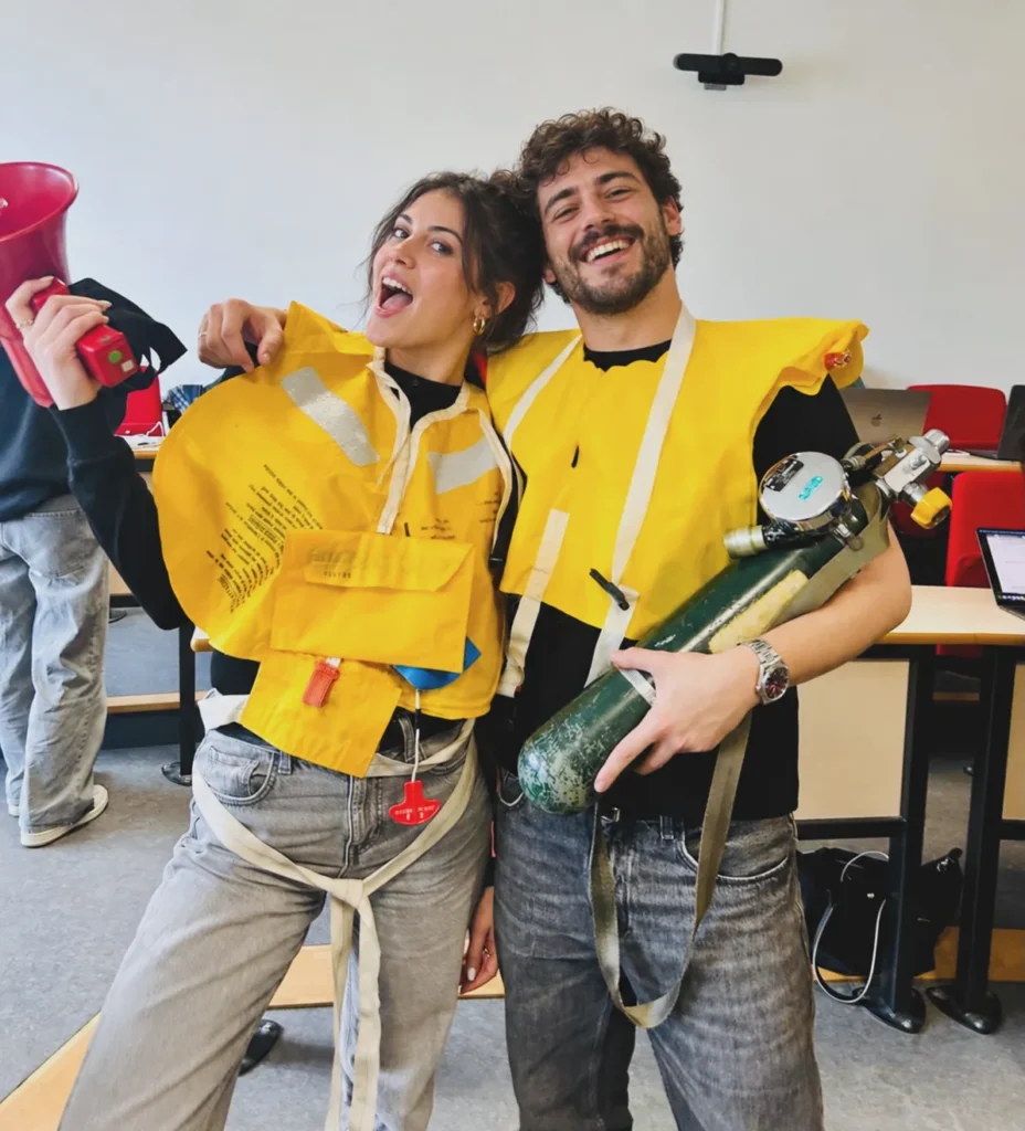 Two trainees in yellow lifejackets handle an oxygen cylinder and a megaphone.